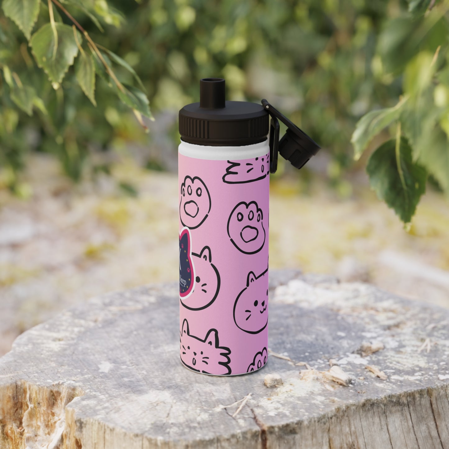 Pink water bottle with black cat illustrations on a wooden log outdoors