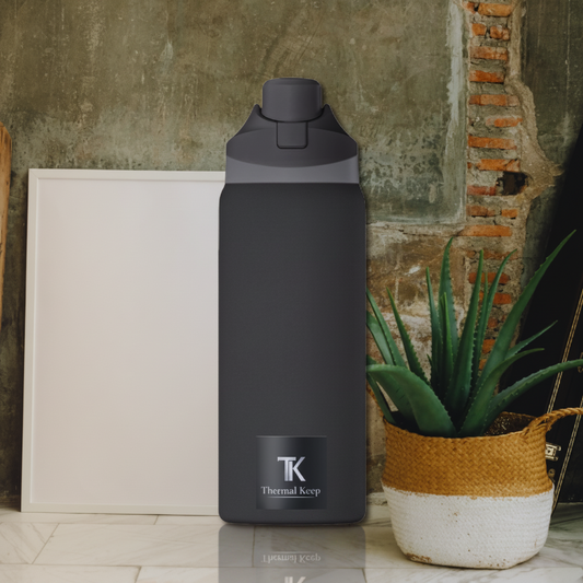 Black water bottle with 'TK' branding against a rustic wall background